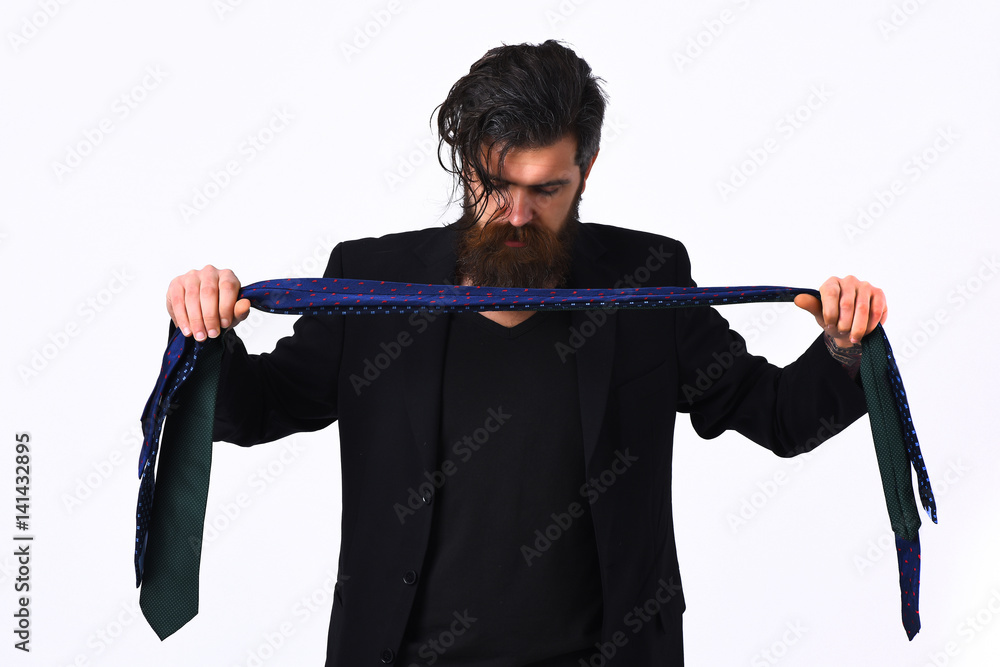 Brutal caucasian hipster in black suit holding ties Brutal caucasian hipster in black suit holding ties