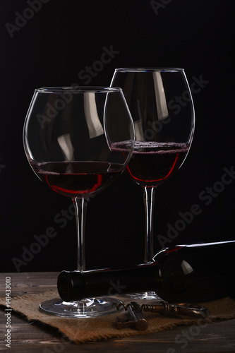 wineglasses with bottle, corkscrew on wooden table with sackcloth napkin