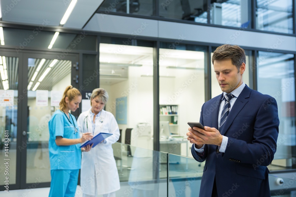 Businessman using mobile while doctor discussing Businessman using mobile while doctor discussing
