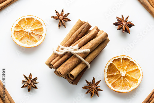 Cinnamon sticks with star orange slices on white background.
