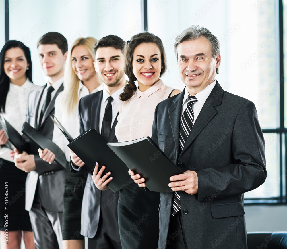 A group of businessmen standing one after another with folders in their hands A group of businessmen standing one after another with folders in their hands