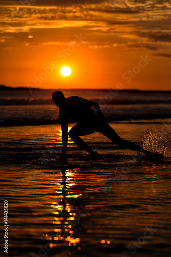 Silhouette of young male capoeira dancer  yoga and martial art specialist at beach in Mexico during spectacular sunset
