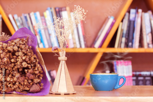 Foto Coffee cup  with  dried flowers on wood table.