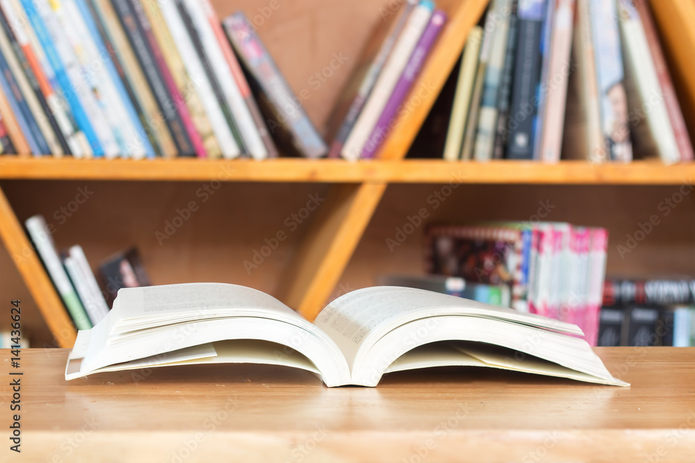 Reading book on wood table against shelf. Reading book on wood table against shelf.