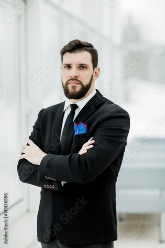 successful businessman standing near a window in bright office.