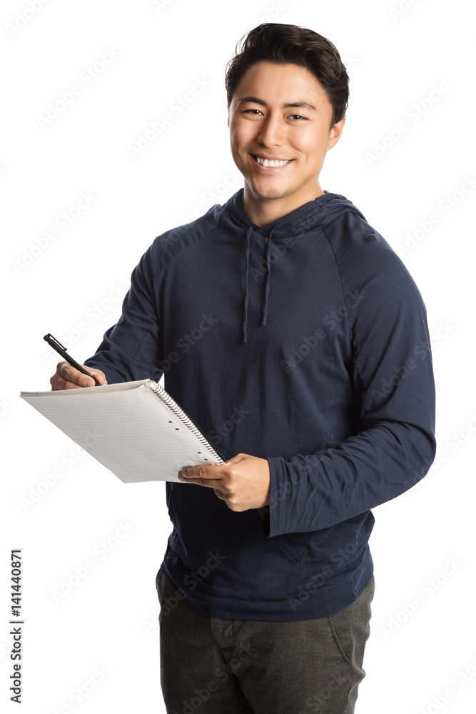 Attractive man wearing a blue hoodie and grey pants standing against a white background holding a pad and paper with a big smile. Attractive man wearing a blue hoodie and grey pants standing against a white background holding a pad and paper with a big smile.