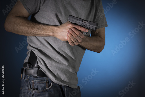 Man drawing a concealed carry pistol from a holster