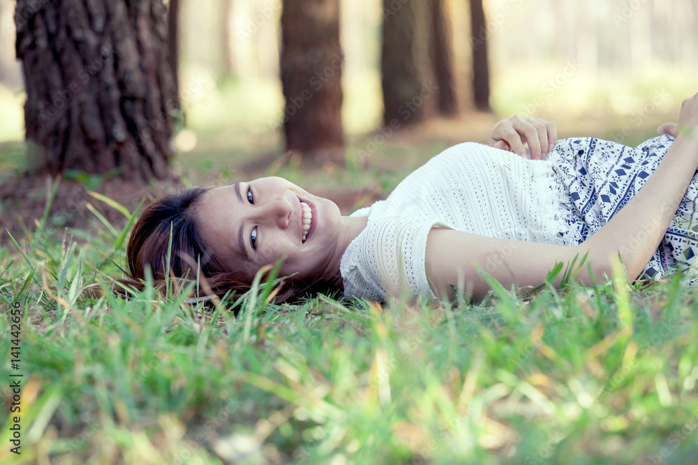 Happy young asian woman lying down on grass in the park in vintage color tone Happy young asian woman lying down on grass in the park in vintage color tone