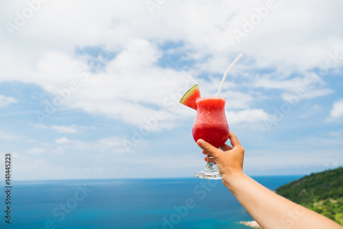 Fruit watermelon neck on an outstretched hand against the background of a tropical landscape. Relaxing holiday.