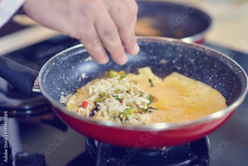 Man's hand holding an egg. White chicken egg. Chef starts preparing omelet.