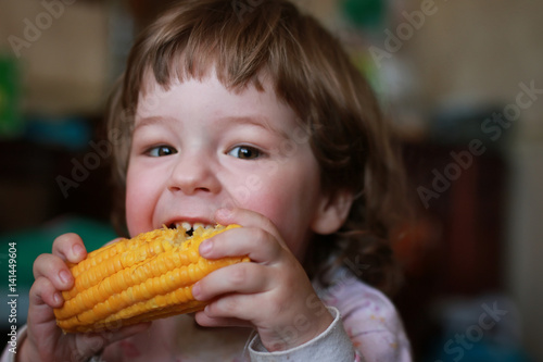 Foto little boy eats greedily biting corn