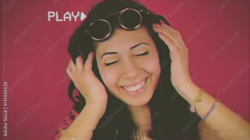 Fake VHS tape: a cute young woman with fancy eyeglasses, having fun while listening to music with headphones. Close-up on red background.
Fake VHS tape: a cute young woman with fancy eyeglasses, having fun while listening to music with headphones. Close-up on red background.