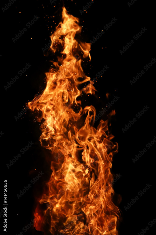 Fototapeta premium Tongues of flame of fire of orange-yellow color from burning firewood