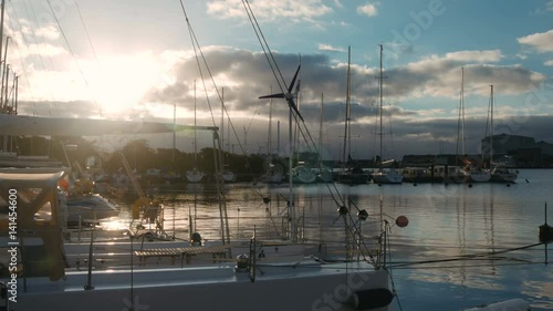 White yachts are laid up. Yacht club, port, harbor. Morning sun is reflecting in the water