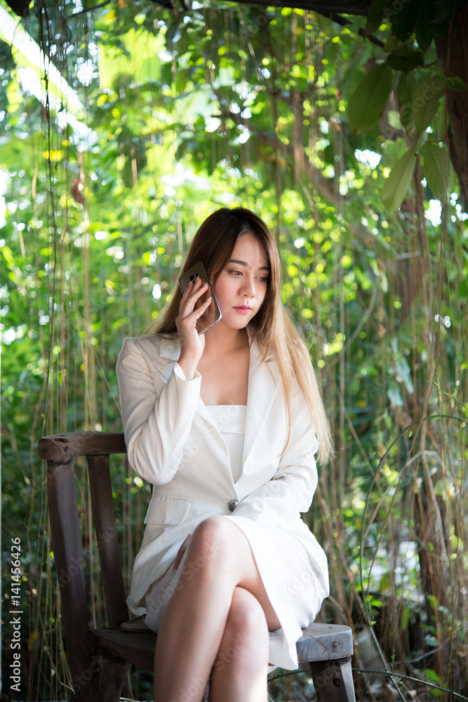 Beautiful businesswoman talking on the mobile phone and smiling while sitting in home garden. Beautiful businesswoman talking on the mobile phone and smiling while sitting in home garden.