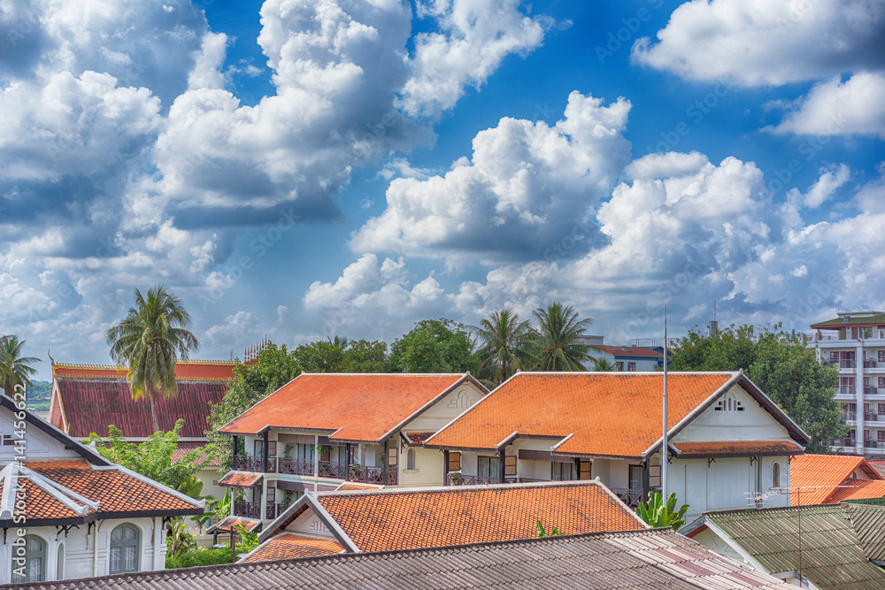 The traditional roofs of house with beatiful clouds on the sky background, Vientiane, Laos
