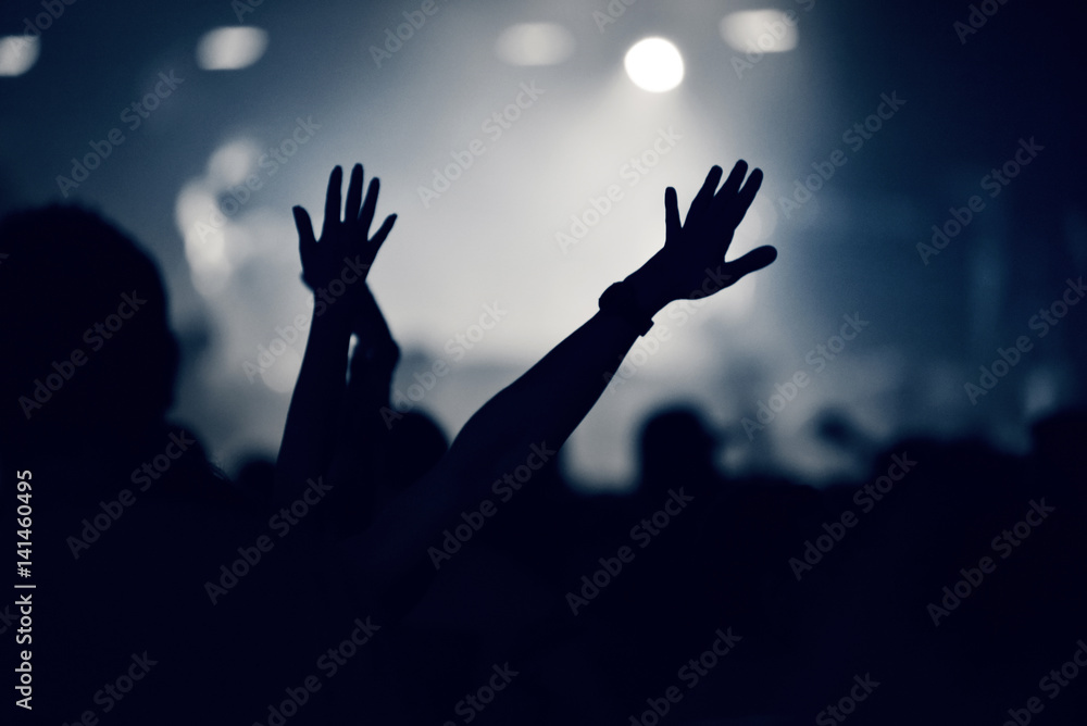 Crowd at a music concert, audience raising hands up, toned