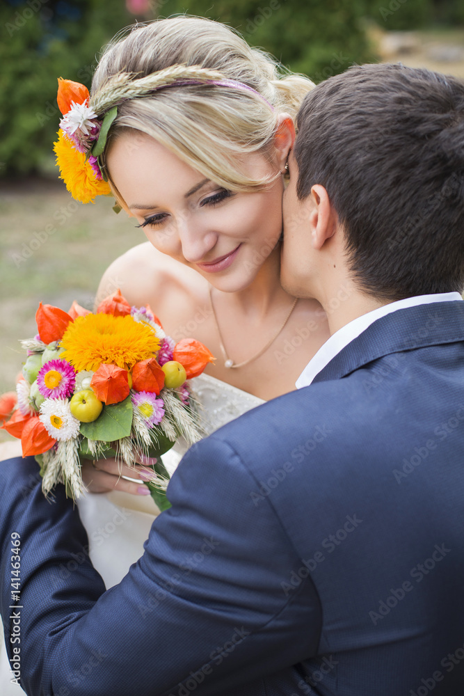 Young couple in wedding gown. Bride holding bouquet of flowers Young couple in wedding gown. Bride holding bouquet of flowers