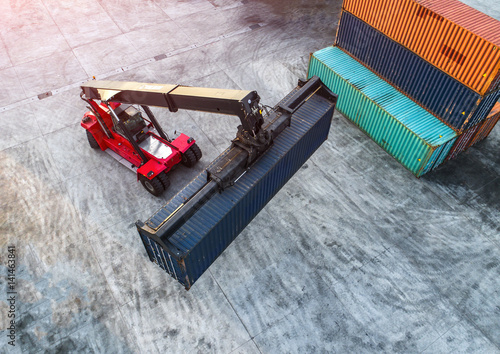 container stacker forklift working on lifting unit of container in yard in aerial view photo