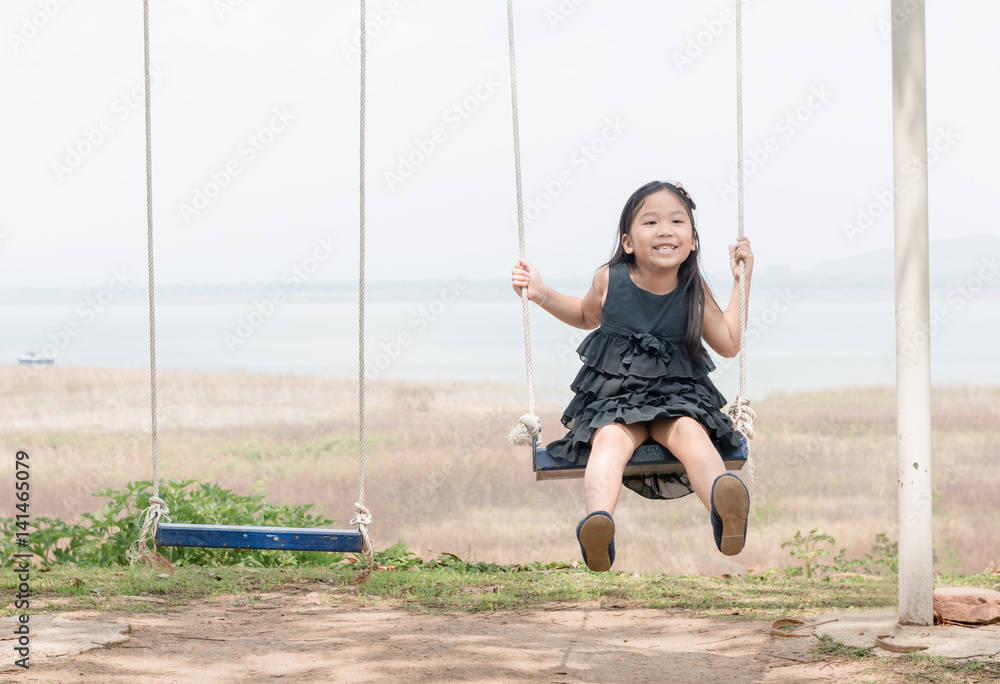 cute girl play swing seat on nature background