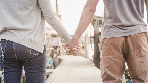 Closeup of loving couple holding hands while walking on the road.