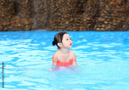 Pretty little girl playing in swimming pool outdoors