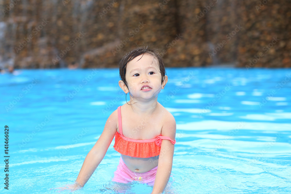 Pretty little girl playing in swimming pool outdoors