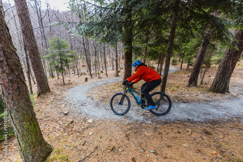 Mountain biker riding on bike in early spring mountains forest landscape. Man cycling MTB enduro flow trail track. Outdoor sport activity.