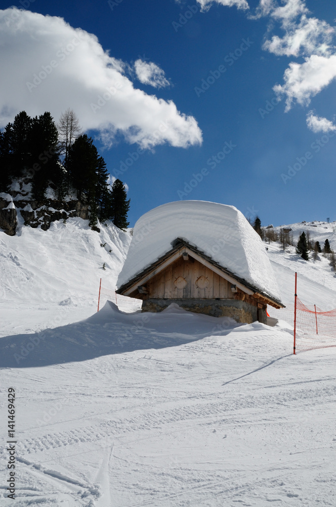 Alpin Hut on the Dolomite Alps with lots of snow on the roof. Winter landscape near the Falzarego Pass, Veneto, italy