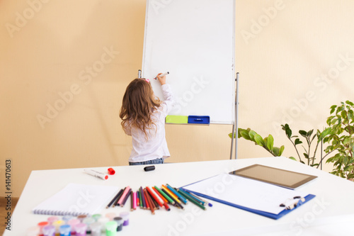 Little girl draws on the white board