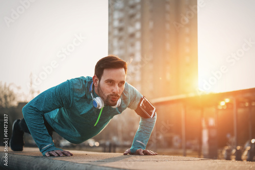 Handsome strong sporty male doing exercises outdoor