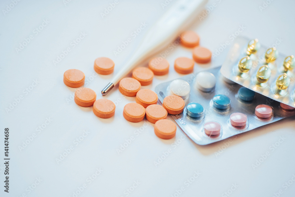 Flu. Thermometer with elevated temperature and many pills on light background Flu. Thermometer with elevated temperature and many pills on light background