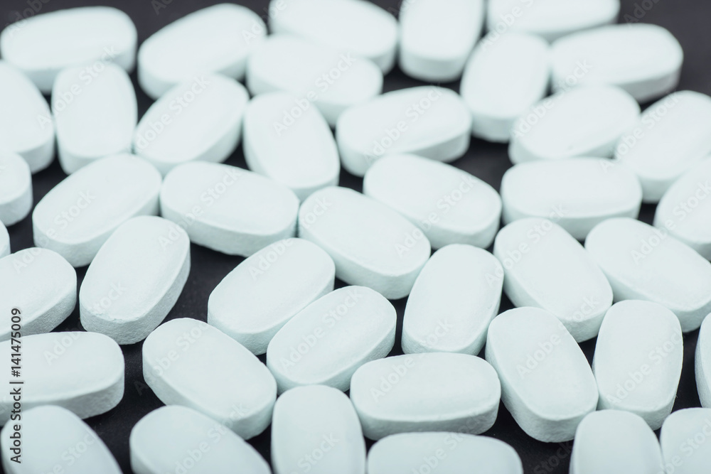 Medical white tablets or supplements for the treatment and health care on a black background Medical white tablets or supplements for the treatment and health care on a black background