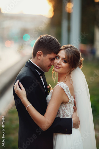 Bride hugs groom tender standing with him calmly on the lawn © myronovychoksana