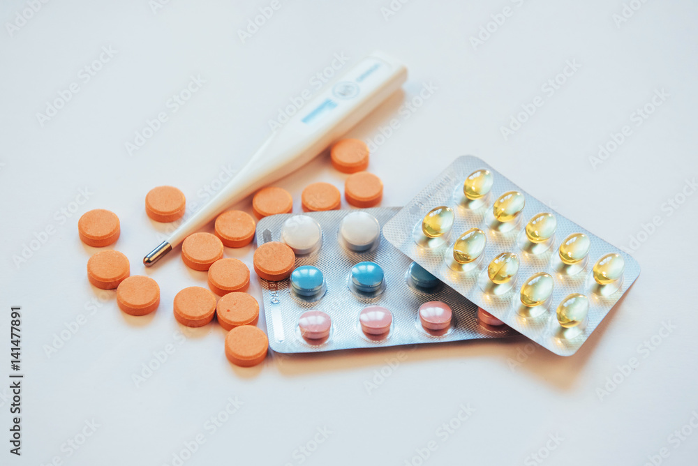 Flu. Thermometer with elevated temperature and many pills on light background Flu. Thermometer with elevated temperature and many pills on light background
