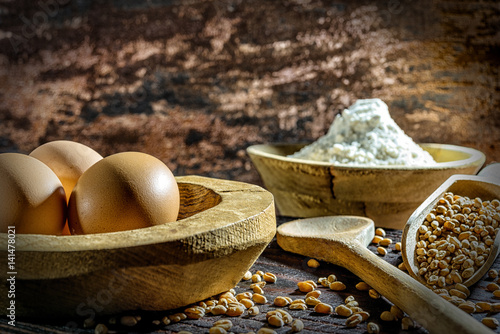 Eier, Weizen,  und Mehl auf Holzbrett