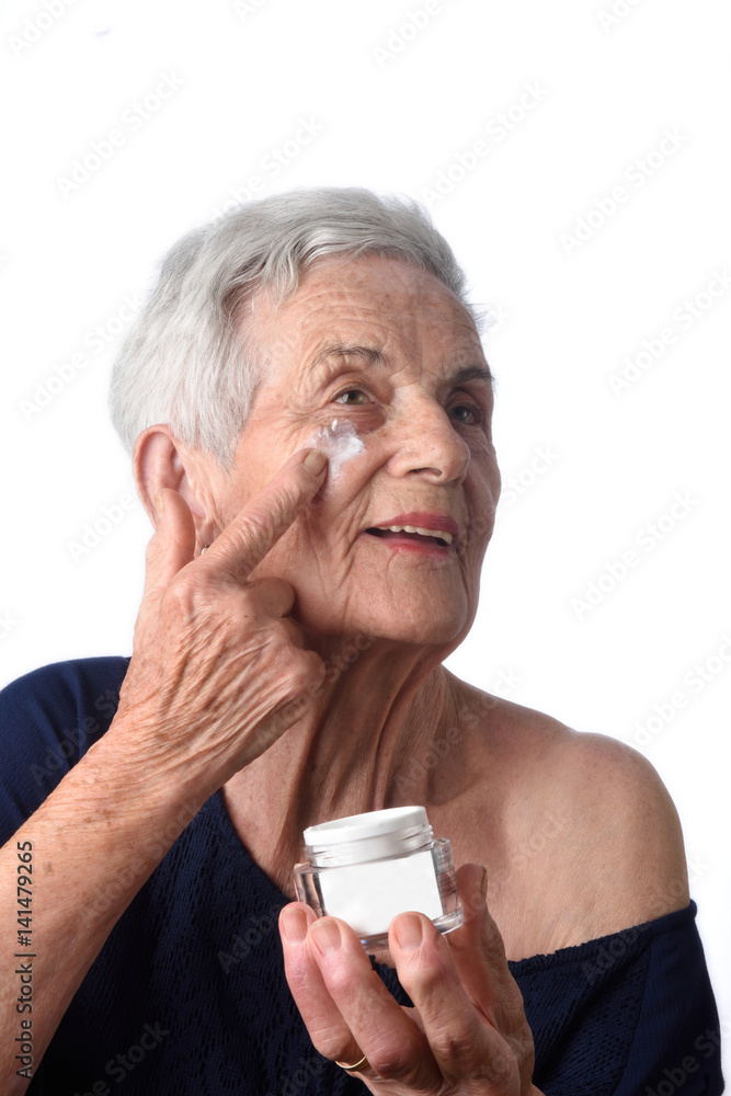 Senior woman applying skin cream or moisturiser to her face Senior woman applying skin cream or moisturiser to her face