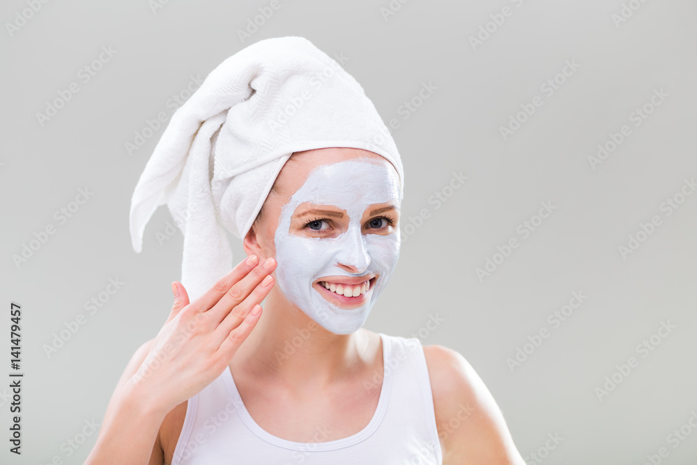 Portrait of young woman with facial mask on gray background. Portrait of young woman with facial mask on gray background.