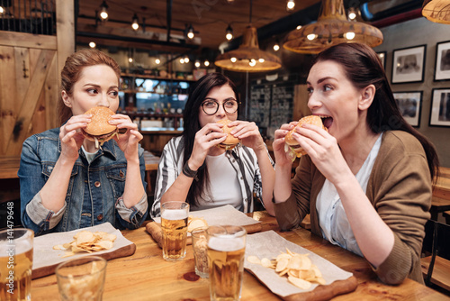 Positive delighted friends eating unhealthy food