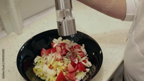 Young beautiful woman preparing a salad in the kitchen. Sprinkle with salt closeup