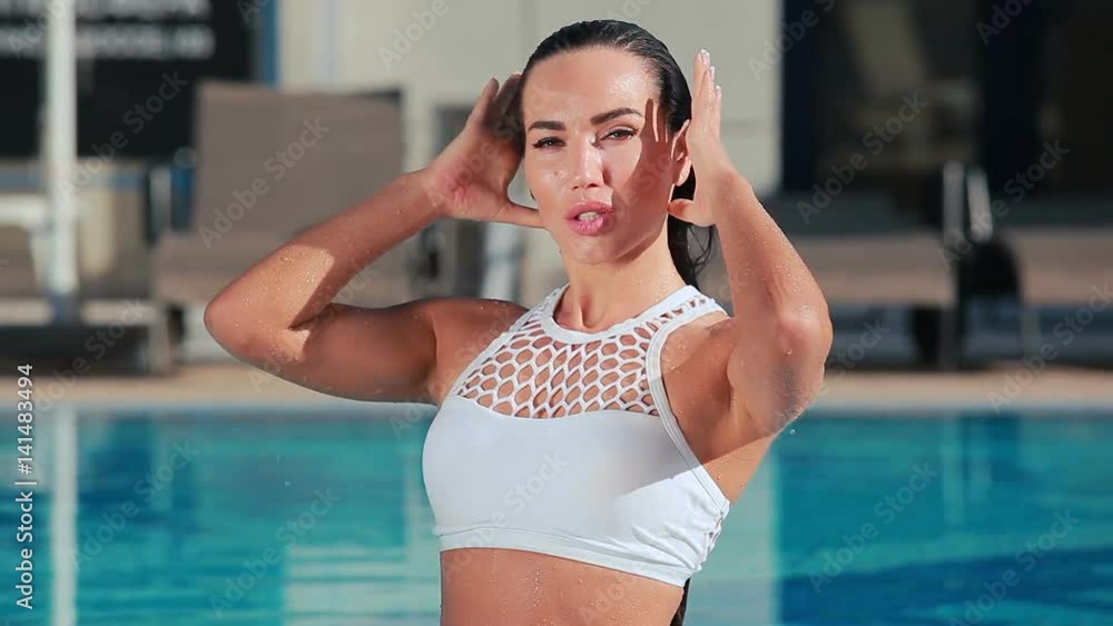 Passionate young woman touches her wet hair in swimming pool Passionate young woman touches her wet hair in swimming pool