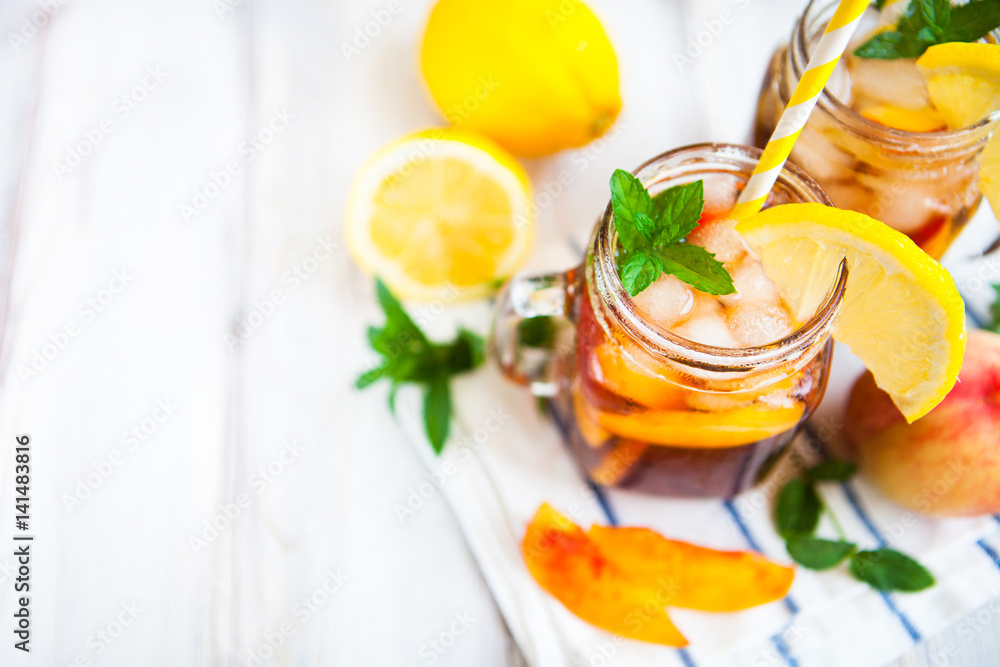 Homemade lemonade with ripe peaches and fresh mint. Fresh peach ice tea on white wood table. Copy space background. Homemade lemonade with ripe peaches and fresh mint. Fresh peach ice tea on white wood table. Copy space background.