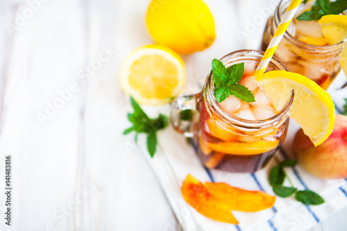 Homemade lemonade with ripe peaches and fresh mint. Fresh peach ice tea on white wood table. Copy space background.