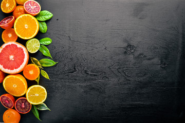 Fresh citrus fruits. Lemon orange, tangerine, lime. On a black background Wooden. Top view.