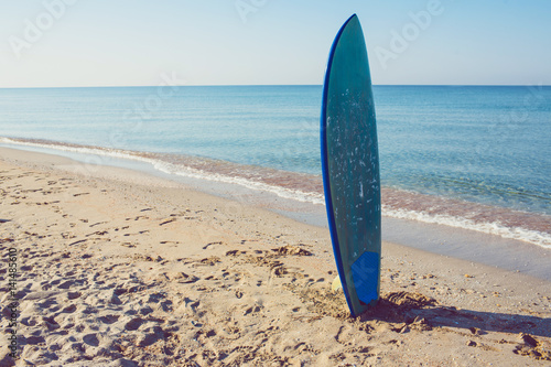 Surf board laying on the sand near the sea