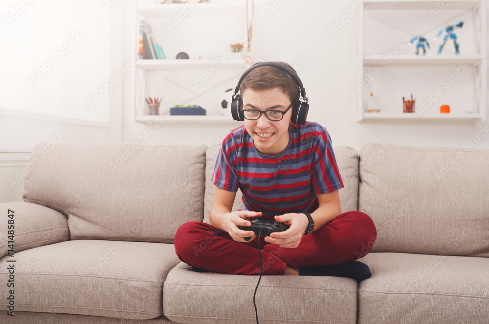 Obraz premium Excited teenage boy playing video game at home