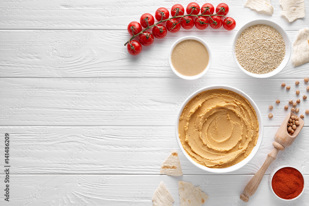 Traditional hummus with ingridients on white table background. Healthy vegetarian nutrition food