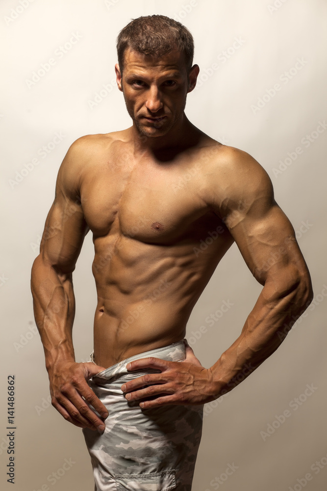 half-naked handsome and muscular young man posing on a gray background half-naked handsome and muscular young man posing on a gray background