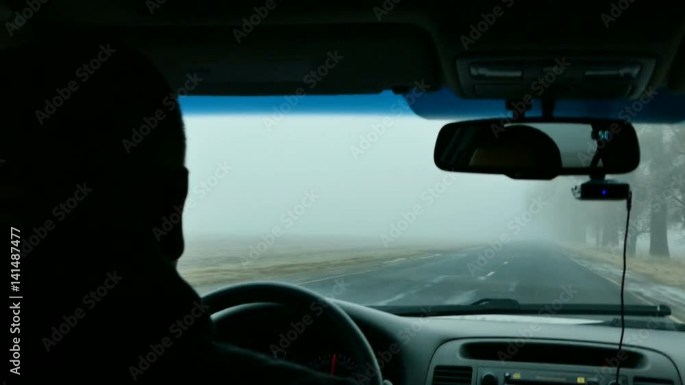 Man's hands of a driver on steering wheel of a car on asphalt road Man's hands of a driver on steering wheel of a car on asphalt road
