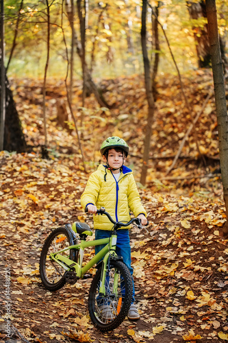 A boy is riding a bicycle in an autumn forest.
